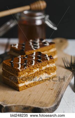 Stock Photography - Slices of layer cake on cutting board with honey. Fotosearch