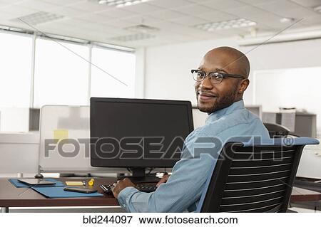 Smiling African American man using computer in office View Large Photo Image Stock Photo - Smiling African American man using computer in office. Fotosearch