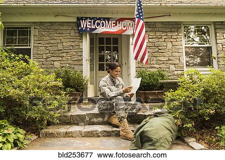 Stock Photo - Smiling African American soldier sitting on front stoop reading letter. Fotosearch