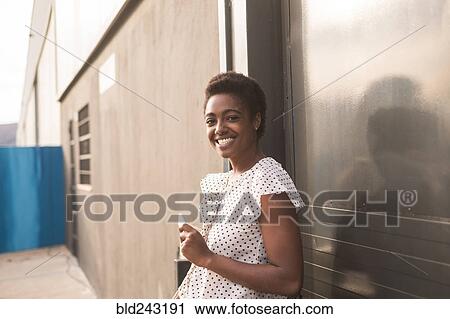 Stock Image - Smiling African American woman holding cell phone. Fotosearch