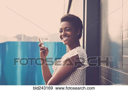 Smiling African American woman holding cell phone View Large Photo Image Stock Photo - Smiling African American woman holding cell phone. Fotosearch