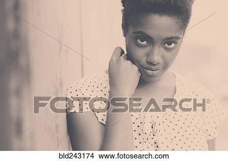 Picture - Smiling African American woman leaning on wall. Fotosearch