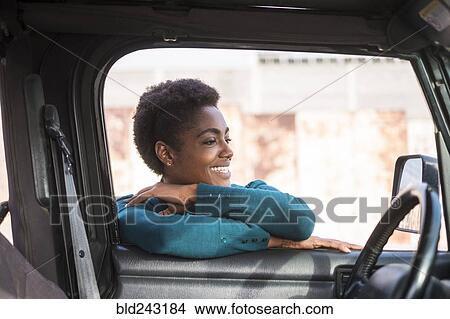 Picture - Smiling African American woman leaning on car window. Fotosearch