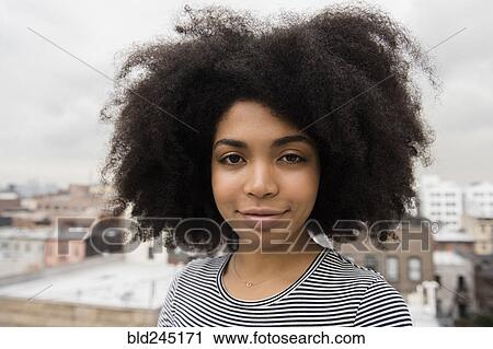 Stock Image - Smiling African American woman posing on rooftop. Fotosearch