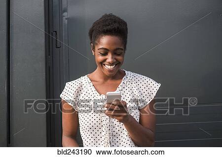 Smiling African American woman texting on cell phone View Large Photo Image Stock Image - Smiling African American woman texting on cell phone. Fotosearch