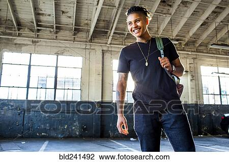 Smiling androgynous Mixed Race woman carrying backpack View Large Photo Image Stock Image - Smiling androgynous Mixed Race woman carrying backpack. Fotosearch