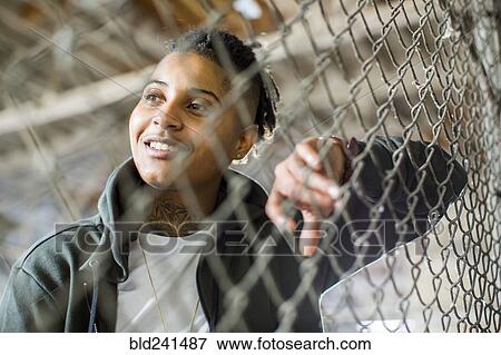 Smiling androgynous Mixed Race woman leaning on fence View Large Photo Image Stock Photo - Smiling androgynous Mixed Race woman leaning on fence. Fotosearch