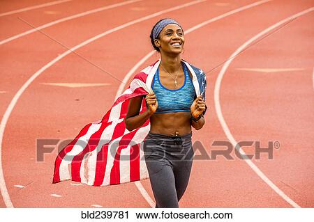 Smiling Black athlete holding American flag on track View Large Photo Image Stock Image - Smiling Black athlete holding American flag on track. Fotosearch