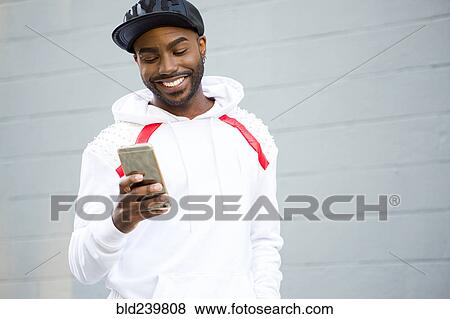 Smiling Black man texting on cell phone View Large Photo Image Stock Photo - Smiling Black man texting on cell phone. Fotosearch