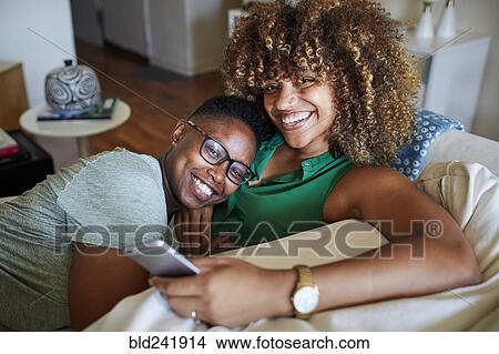 Smiling Black women cuddling on sofa View Large Photo Image Picture - Smiling Black women cuddling on sofa. Fotosearch