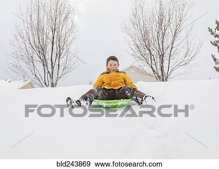 Smiling boy sliding on toboggan on hill in winter View Large Photo Image Stock Photo - Smiling boy sliding on toboggan on hill in winter. Fotosearch