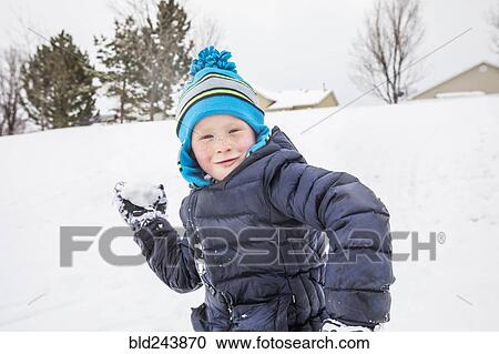 Stock Image - Smiling boy throwing snowball in winter. Fotosearch