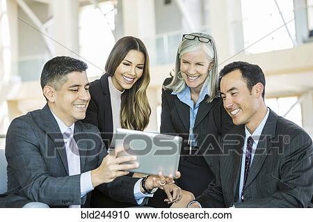 Smiling business people reading digital tablet in lobby View Large Photo Image Stock Image - Smiling business people reading digital tablet in lobby. Fotosearch