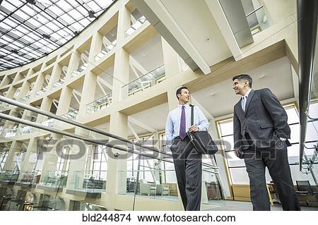 Smiling businessmen talking and walking in lobby View Large Photo Image Picture - Smiling businessmen talking and walking in lobby. Fotosearch