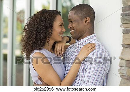 Stock Photograph - Smiling call leaning on wall and hugging. Fotosearch