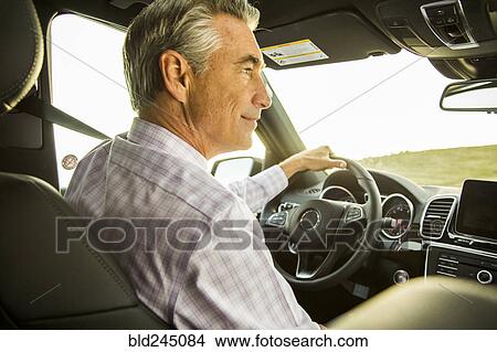Picture - Smiling Caucasian businessman driving car. Fotosearch