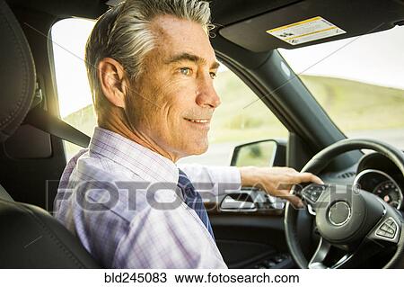 Stock Image - Smiling Caucasian businessman driving car. Fotosearch