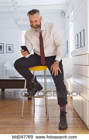 Stock Photo - Smiling Caucasian businessman texting on cell phone. Fotosearch