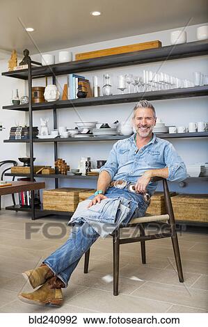 Smiling Caucasian man relaxing on chair in store View Large Photo Image Stock Image - Smiling Caucasian man relaxing on chair in store. Fotosearch