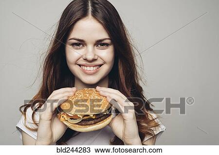 Smiling Caucasian woman holding cheeseburger View Large Photo Image Stock Image - Smiling Caucasian woman holding cheeseburger. Fotosearch