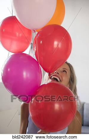 Smiling Caucasian woman holding multicolor helium balloons View Large Photo Image Stock Photo - Smiling Caucasian woman holding multicolor helium balloons. Fotosearch