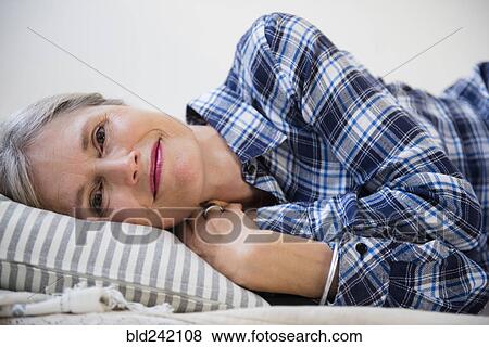 Stock Photo - Smiling Caucasian woman laying on pillow. Fotosearch