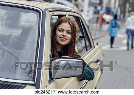 Stock Photo - Smiling Caucasian woman leaning on door driving car. Fotosearch
