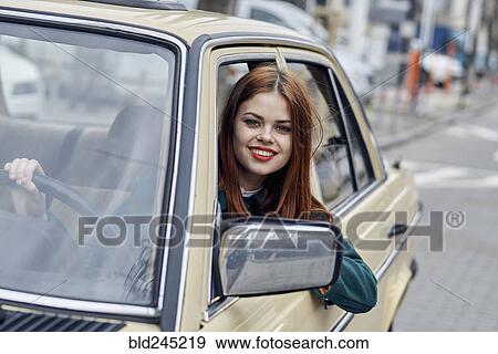 Smiling Caucasian woman leaning on door driving car View Large Photo Image Stock Photo - Smiling Caucasian woman leaning on door driving car. Fotosearch