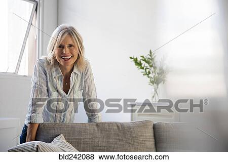 Smiling Caucasian woman leaning on sofa View Large Photo Image Stock Photo - Smiling Caucasian woman leaning on sofa. Fotosearch