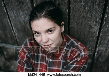 Stock Photography - Smiling Caucasian woman leaning on wooden door. Fotosearch