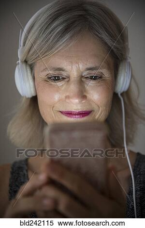 Stock Photography - Smiling Caucasian woman listening to music on cell phone. Fotosearch