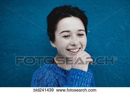 Stock Photo - Smiling Caucasian woman near blue wall. Fotosearch