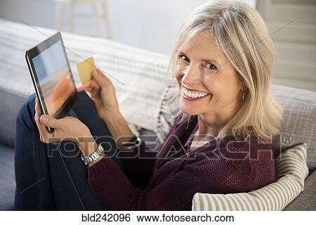 Smiling Caucasian woman online shopping with digital tablet View Large Photo Image Stock Photograph - Smiling Caucasian woman online shopping with digital tablet. Fotosearch