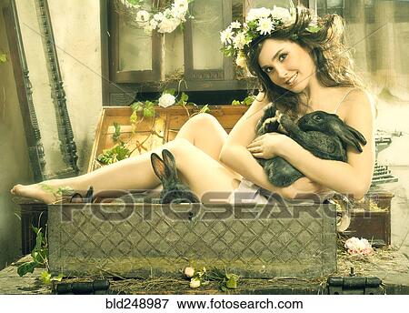 Smiling Caucasian woman sitting in trunk holding rabbit View Large Photo Image Stock Photo - Smiling Caucasian woman sitting in trunk holding rabbit. Fotosearch