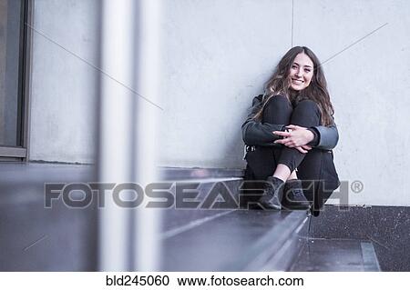 Stock Image - Smiling Caucasian woman sitting on staircase. Fotosearch