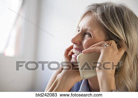 Stock Image - Smiling Caucasian woman talking on cell phone. Fotosearch