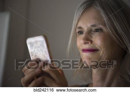 Stock Photograph - Smiling Caucasian woman texting on cell phone. Fotosearch