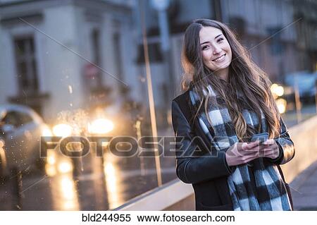 Stock Photography - Smiling Caucasian woman texting on cell phone outdoors. Fotosearch