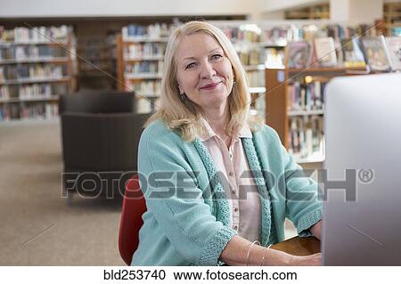Smiling Caucasian woman using computer in library View Large Photo Image Stock Image - Smiling Caucasian woman using computer in library. Fotosearch