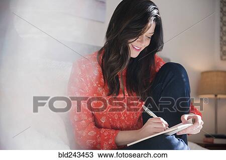 Smiling Caucasian woman writing on notepad View Large Photo Image Stock Image - Smiling Caucasian woman writing on notepad. Fotosearch