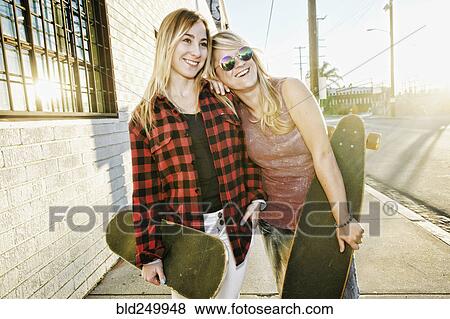 Smiling Caucasian women holding skateboards on sidewalk View Large Photo Image Stock Photo - Smiling Caucasian women holding skateboards on sidewalk. Fotosearch