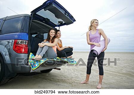Picture - Smiling Caucasian women on beach with car. Fotosearch