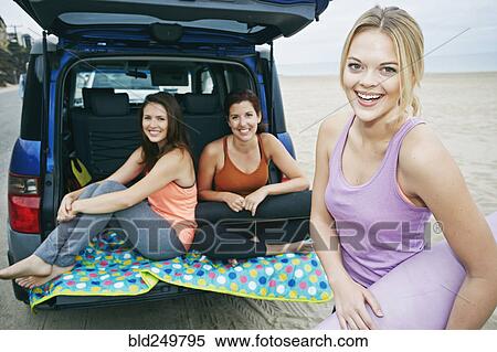 Stock Photography - Smiling Caucasian women on beach with car. Fotosearch