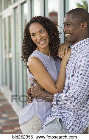 Smiling couple leaning on wall and hugging View Large Photo Image Stock Photography - Smiling couple leaning on wall and hugging. Fotosearch