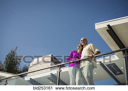 Smiling couple standing on modern balcony View Large Photo Image Stock Image - Smiling couple standing on modern balcony. Fotosearch