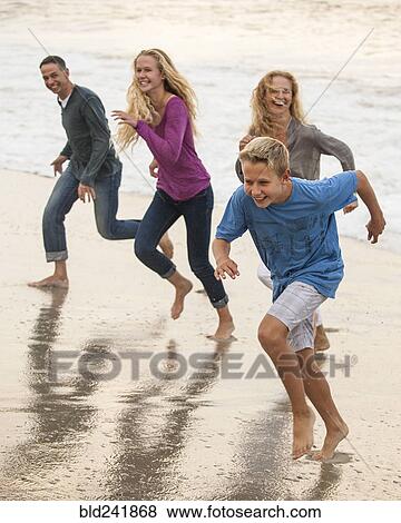Stock Photo - Smiling family running on beach. Fotosearch