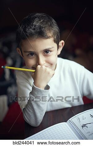 Stock Image - Smiling Hispanic boy practicing writing alphabet. Fotosearch
