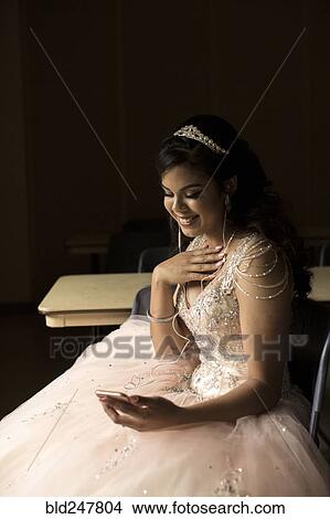 Picture - Smiling Hispanic girl listening to cell phone with earbuds. Fotosearch