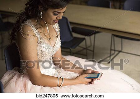 Smiling Hispanic girl listening to cell phone with earbuds View Large Photo Image Stock Photography - Smiling Hispanic girl listening to cell phone with earbuds. Fotosearch