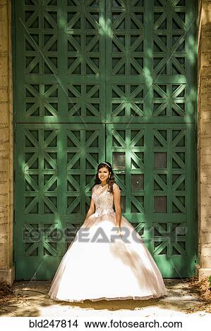 Picture - Smiling Hispanic girl wearing gown near green wall. Fotosearch